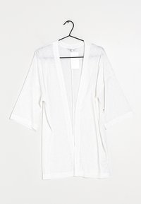 Lekki biały kardigan w stylu kimono z krótkimi rękawami, otwartym przodem i subtelną teksturą. Wiszący na czarnym haczyku. Dołączona metka.