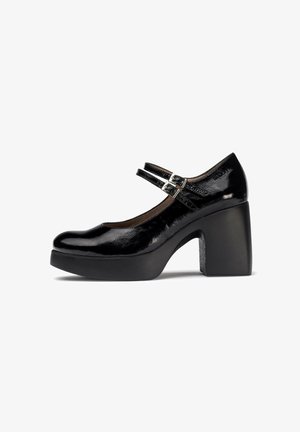 Zapato Mary Jane de charol negro con punta redondeada, tacón grueso de bloque y dobles correas ajustables con una hebilla metálica.