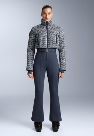 Marinblå texturerad jacka med hög krage, kombinerad med figurnära marinblå byxor med utställda byxben. Svarta stövlar med en glänsande finish fulländar looken.
