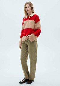 Röd och beige randig stickad tröja med krage, matchad med olivgröna vida byxor och mörkbruna skor.