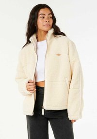 Fleece ritjack in crèmekleur, met een hoge kraag, voorzakken en een textuurstof met een relaxte pasvorm. Ritsdetail aan de voorkant.