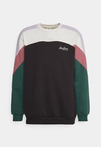 Felpa a colori blocchi con corpo nero e maniche color crema, lavanda, rosa e verde. Tessuto morbido con polsini e orlo a costine. Logo "downtown kaotiko" sul petto.