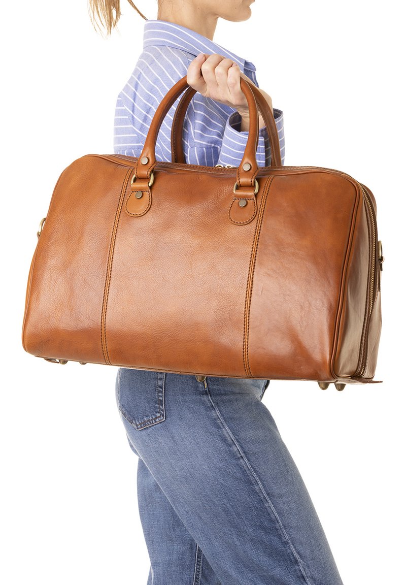 Sac de voyage en cuir marron avec deux poignées supérieures, coutures visibles et détails en métal argenté. Forme rectangulaire avec une texture lisse et brillante.