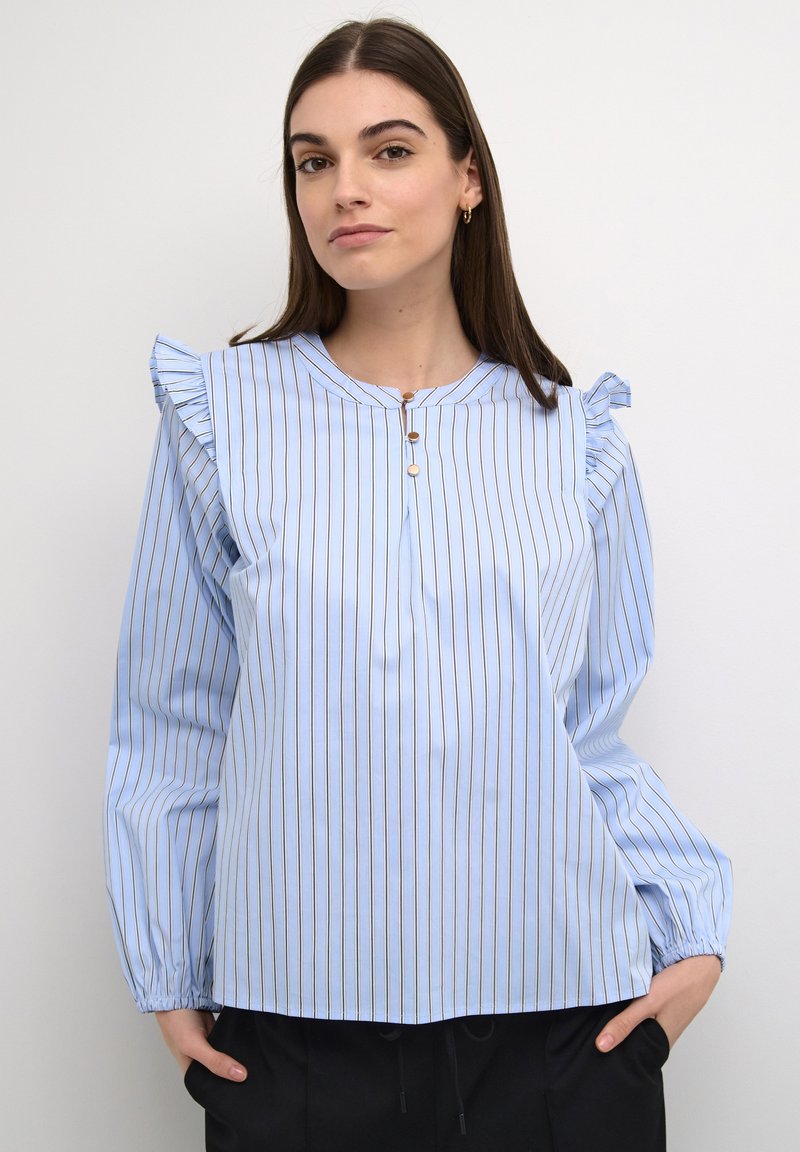 Blusa a maniche lunghe azzurro chiaro con strisce verticali, caratterizzata da spalle arricciate e scollatura con bottoni. Tessuto morbido al tatto.