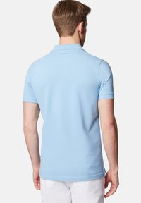 Jasnoniebieska koszulka polo z krótkim rękawem o miękkiej teksturze, z kołnierzykiem i małym logo na tylnej części dekoltu.