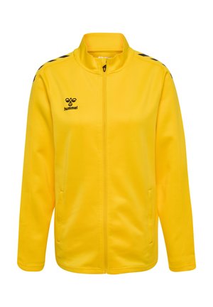 Gelbe Zip-Jacke aus glattem Stoff, mit hohem Kragen, Seitentaschen und schwarzen Akzenten an den Schultern. Hummel-Logo auf der Brust.