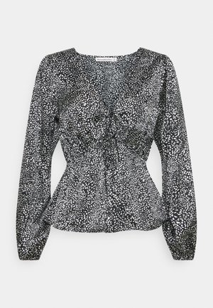 Blouse noire manches longues avec motif de points blancs irréguliers, lien froncé sur le devant et taille légèrement évasée par Abercrombie & Fitch.