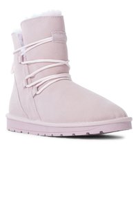 Stivale in suede rosa chiaro con fodera in pelliccia sintetica, punta arrotondata e dettagli in pizzo. La suola in gomma piatta presenta scanalature antiscivolo per stabilità.