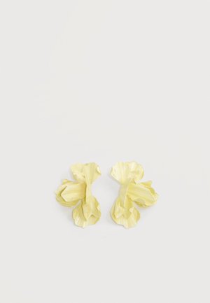 Par af lysegule øreringe formet som blomster med lagdelte, strukturerede kronblade på en lys baggrund.