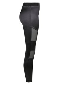 Zwarte legging gemaakt van soepel, rekbaar materiaal met meshpanelen aan de zijkanten. Kenmerkt zich door een hoge tailleband en een aansluitend ontwerp.