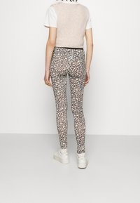 Leggings con estampado floral en una tela elástica, con una base oscura y colores claros, cintura alta y un diseño ajustado.