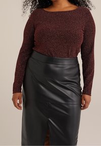 Top lungo a maniche lunghe di colore bordeaux con texture, abbinato a una gonna nera in ecopelle con spacco frontale e finitura liscia.