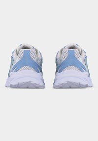 Ζευγάρι αθλητικών παπουτσιών με μπλε και λευκό πλέγμα, εμφανιζόμενα από πίσω σε λευκό φόντο, τονίζοντας τις χοντρές λευκές σόλες τους.