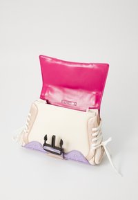 Sac à main tricolore avec des matériaux beiges, roses et violets, intérieur rose brillant, détails en dentelle et fermeture en métal noir.