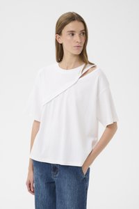 Balti trumpomis rankovėmis marškinėliai iš minkšto medvilnės audinio, su asimetriniu dizainu ir įstrižine išpjova ant vieno peties. Derinama su mėlynomis džinsais.