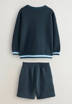 Mørkeblå sweatshirt med vaffelmønster, ribbede ærmer og en stribet kant forneden, parret med matchende ensfarvede mørkeblå shorts med elastisk talje.