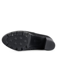 Zapato de cuero negro con un tacón robusto, que presenta una superficie lisa y una suela de goma con patrón que posee seis tracciones en forma de estrella para mayor agarre.