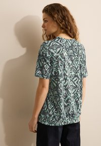 Top de manga corta y cuello redondo con un estampado abstracto multicolor en tonos de azul verdoso, gris y negro, con un corte relajado.