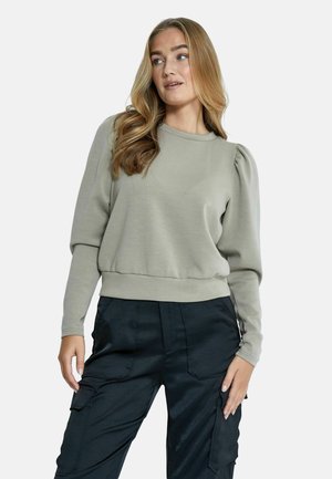 Felpa grigia chiara con design delle spalle a sbuffo, orlo a coste e tessuto testurizzato. Abbinata a pantaloni cargo neri con tasche.