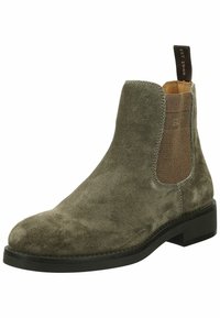 Tmavě zelené semišové Chelsea boty s elastickými bočními panely, zakulacenou špičkou a nízkým černým gumovým podpatkem. Vzadu má hnědou poutko.