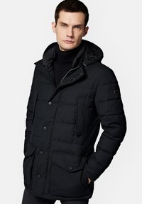 Czarna kurtka puchowa z kapturem, z kwadratowym pikowaniem, zapięciem na guziki i dwoma przednimi kieszeniami. Teksturowana tkanina o matowym wykończeniu.