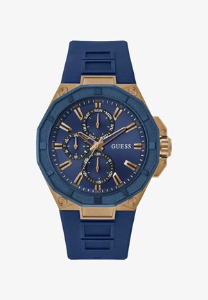 Zegarek na niebieskim silikonowym pasku z ośmiokątną złotą kopertą, teksturowanym niebieskim cyferblatem, trzema podcyferblatami, złotymi znacznikami godzin oraz logo GUESS.