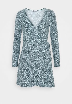 Pitkähihaista kietaisumekkoa tummanvihreänä, jossa on valkoinen kukkakuosi, V-pääntie ja vyötäröllä nauhatyksit, valmistettu pehmeästä kankaasta.