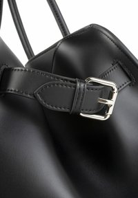 Schwarze Lederhandtasche mit einem flachen Riemen und einer silbernen Schnalle, glatter Oberfläche und genähten Details entlang der Kanten.