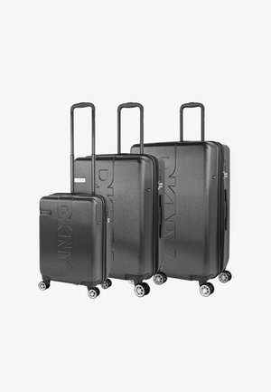 Tres maletas rígidas negras con asas telescópicas y cuatro ruedas, dispuestas por tamaño de la más pequeña a la más grande, con el logo de DKNY.