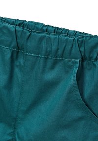 Pantalons teal à taille élastique avec taille froncée et poches latérales, fabriqués dans un tissu lisse avec un subtil éclat et des détails de couture soignés.