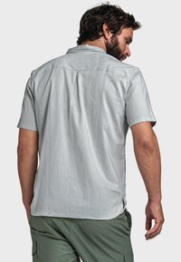 Helles graues Kurzarmhemd mit Button-Down-Kragen, strukturiertem Stoff und Rückenfalten, kombiniert mit olivgrünen Cargo-Shorts.