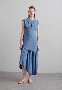 Jurk van denim met korte mouwen, een aangesloten lijfje en een uitlopende, asymmetrische zoom. Lichtblauwe kleur met geplooide details bij de taille.