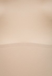 Nude vientisos audinys su lygiu paviršiumi, suformuotas prigludusiu pavidalu. Pabrėžia subtilią horizontalinę siūlę per vidurį.