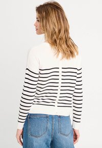 Hvid og marineblå stribet cardigan med knaplukning på bagsiden, ribbede manchetter og kant, lavet af et blødt strikkemateriale. Velegnet til hverdag.
