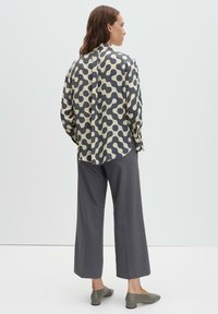 Long-sleeve shirt in blue and beige abstract pattern, paired with gray wide-leg trousers and olive green slip-on shoes. Soft fabric, relaxed fit.