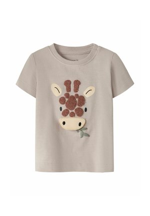 Camiseta beige para niño pequeño con una aplicación de la cara de una jirafa texturizada que sostiene hojas verdes en la boca en el centro delantero.