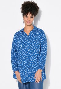 Blå långärmad skjorta i ett lätt tyg, med ett hjärtformat m�önster i vitt och mörkblått. Knappstängning framtill med krage.