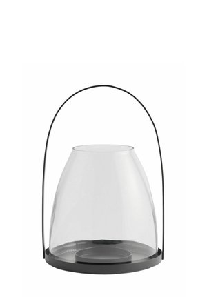 Transparente Glaslaterne mit schwarzem Metallfuß und gebogenem Griff, die dafür ausgelegt ist, eine Kerze innen zu halten.