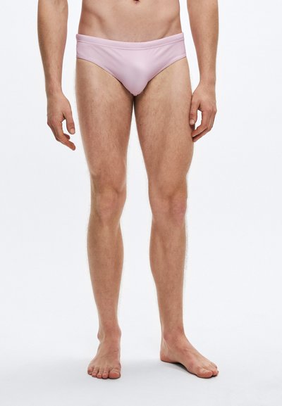 Male swim briefs in light pink, made of smooth, stretchy fabric. Features a low-rise design and minimal coverage.