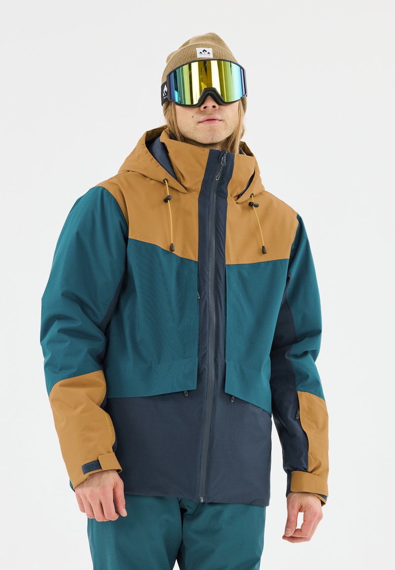 Weather-resistant jacket featuring a three-color design: teal, brown, and navy, with a hood, adjustable cords, and a zip front. Smooth texture.