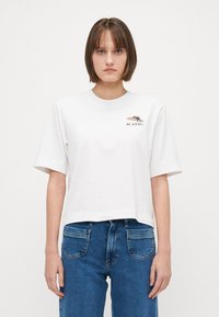 Tricou alb scurt din bumbac moale, cu guler rotund. Prezintă un mic design grafic cu text în zona stângă a pieptului.