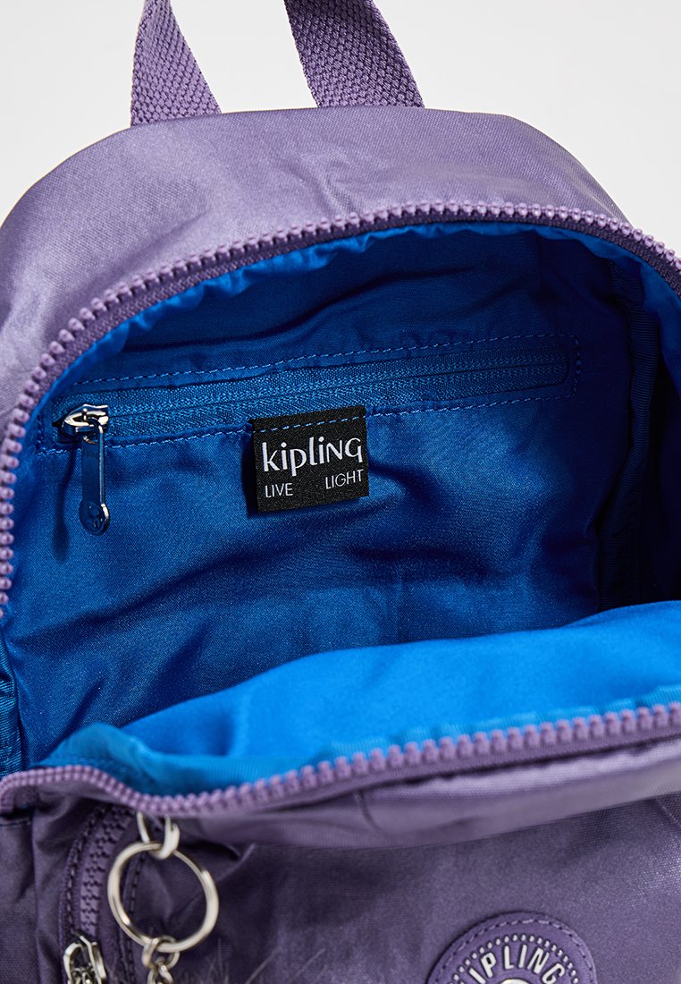 Sac à dos Kipling violet avec un compartiment zippé et une doublure bleu vif. Il est doté d'un logo cousu et de quincaillerie pour porte-clés. Matériau extérieur texturé.
