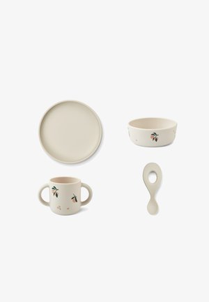 Juego de vajilla beige para niños pequeños que incluye un plato redondo, un bol, una taza con dos asas con diseños de frutas y una cuchara con un agujero grande en el mango.