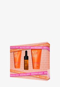 Das NIP+FAB Hautpflege-Set umfasst drei Produkte in lebhaft orangefarbenen Tuben und eine Pipettenflasche, verpackt in einer farbenfrohen Box mit hervorgehobenen Texten.