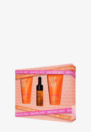 Il set di skincare NIP+FAB presenta tre prodotti in vivaci tubi arancioni e una bottiglia con contagocce, confezionati in una scatola colorata con testi in evidenza.