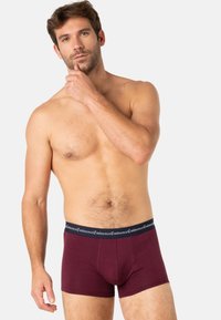 Caleçons boxers bordeaux avec une ceinture noire arborant une marque. Texture lisse, design ajusté et ceinture élastique pour plus de confort.