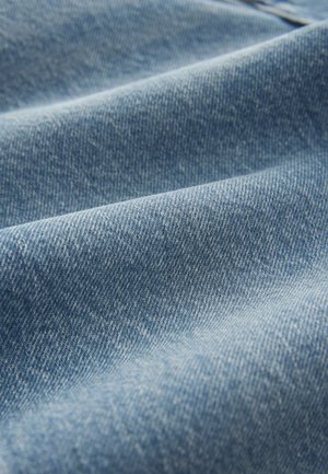 Denim w średnim niebieskim kolorze o lekko teksturowanym, tkanym wyglądzie, z miękkimi fałdami i zagięciami na całej powierzchni.
