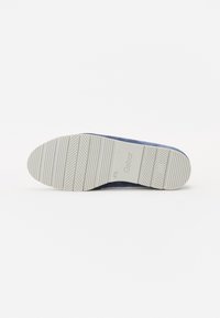 Chaussure bleu marine avec une semelle en caoutchouc gris texturée présentant des rainures et le logo « Gabor ». La forme de la semelle est arrondie avec une légère courbe.