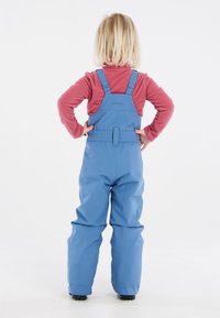 Blå vattentäta overaller med justerbara remmar och en åtsittande midja. Tyget är slätt med en matt yta, utformat för utomhusbruk.