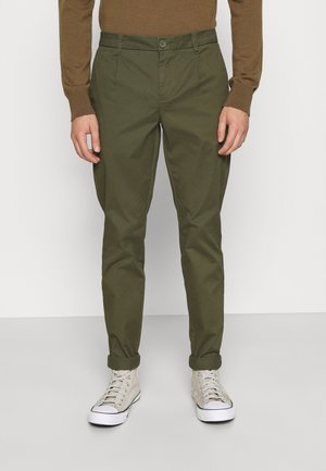 Chinos en coton vert olive avec une coupe slim, dotés d'une fermeture à un bouton et de poignets retroussés, associés à des baskets montantes grises claires.